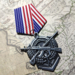 V&auml;ljam&otilde;eldud Ameerika kontinentaalsaavutuste medal, tsingisulamist topeltp&uuml;ssirist oliivioks, mis &uuml;mbritseb retrolavastust #1